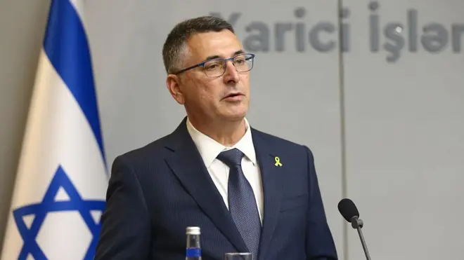 İsrail Dışişleri Bakanı Gideon Saar basın toplantısında. Arkasında İsrail bayrağı var.