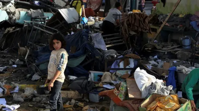 Devojčica stoji među ruševinama škole u Gazi koja je pogođena tokom izraelskog vazdušnog napada