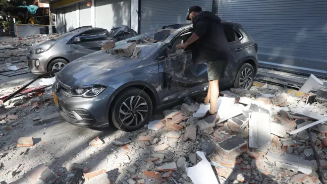 Um homem observa um veículo danificado após um terremoto em Cali, Colômbia, em 10 de agosto de 2026. Um terremoto de magnitude 7,4 abalou grande parte da Colômbia, segundo o Serviço Geológico Colombiano (SGC), e as autoridades relataram danos em várias cidades, incluindo Manizales, Cali e Pereira.