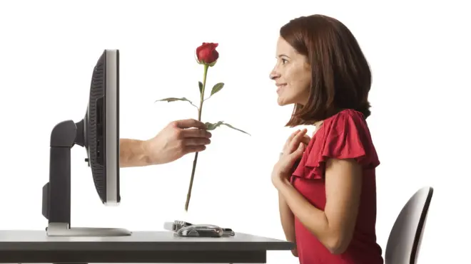 mujer recibiendo una rosa que sale de su computadora