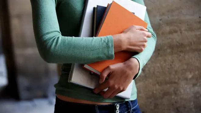 An anonymous woman with books and a computer