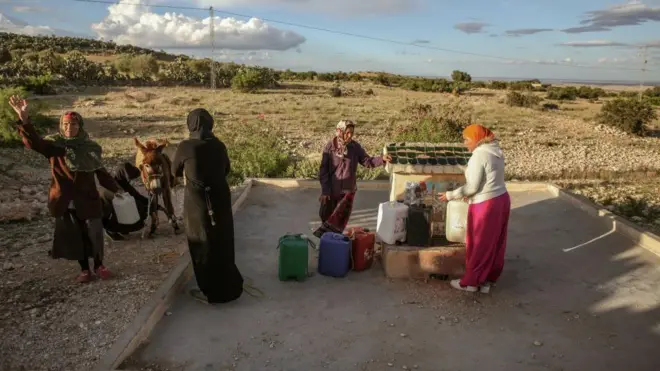 نساء يملأن حاويات من ماء صنبور مشترك.