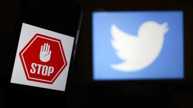 Un panneau stop à côté du logo Twitter