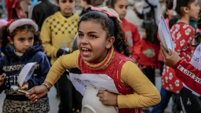 کودکان فلسطینی روز گذشته با در دست داشتن بنرها و کاسه‌های خالی به کمبود مواد غذایی در غزه اعتراض می‌کنند