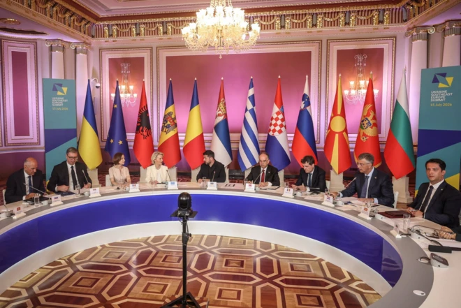 Ljudi sede za okruglim stolom, iza njih zastave zemalja, učesnica samita u Kijevu