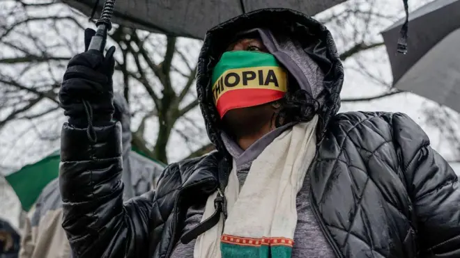 ዣንጥላ የያዘ እና ኢትዮጵያ የሚል ጽሁፍ ያለበት ማስክ ያደረገ ሰው