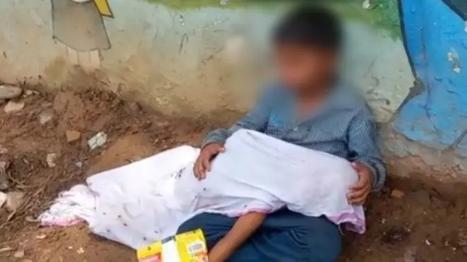 मध्यप्रदेश के मुरैना में छोटे भाई का शव गोद में लिए बैठा बच्चा.