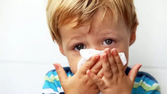 Toddler boy blowing his nose