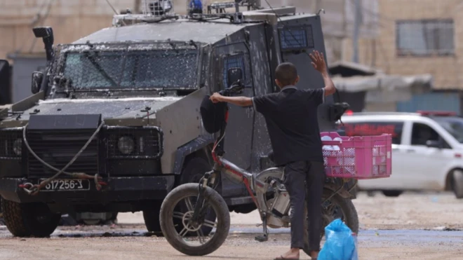Un menor palestino frente a un vehículo del ejército israelí en Cisjordania.