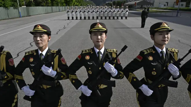 身穿墨绿色制服的中国解放军联合军乐团女团员手持步枪在北京集训点参与9月3日阅兵训练(20/8/2025)