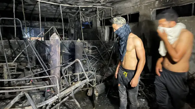 رجلان داخل أحد أجنحة المستشفى المتفحمة