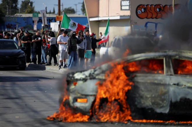 Manifestantes perto de um carro em chamas após várias detenções pelo Serviço de Imigração e Alfândega (ICE), na cidade de Compton, no Condado de Los Angeles, Califórnia, EUA, em 7 de junho