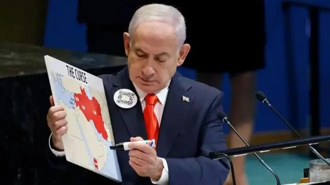 نتانیاهو به نقشهای که در دست دارد نگاه میکند؛ بخشی از ترکیه و همسایگان جنوبشرقی آن دیده میشود. همسایگان با رنگ قرمز علامتگذاری شدهاند. در دست دیگرش یک ماژیک است
