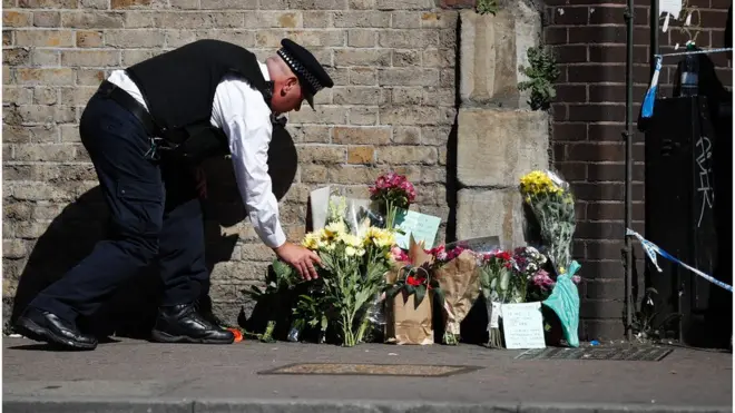 Seorang polisi meletakkan karangan bunga di lokasi penabrakan minibus dekat sebuah masjid di Finsburk Park, London utara.