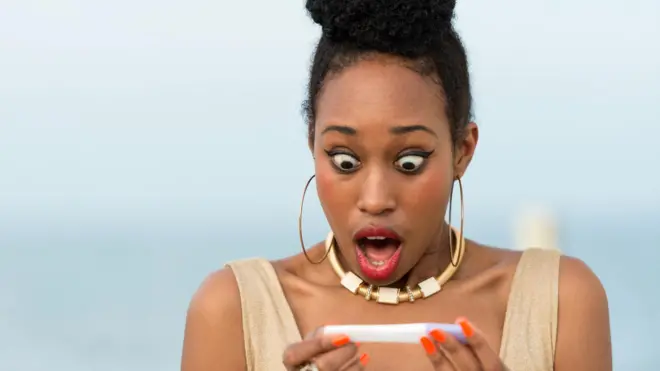 Woman dey look pregnancy test strip