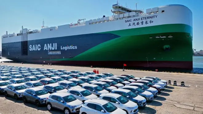 港に停泊する中国のコンテナ船。港には新車が並んでいる