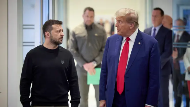 Prezydent Ukrainy Wołodymyr Zełenski i prezydent USA Donald Trump stoją obok siebie, odwracając głowy, by spojrzeć na siebie.