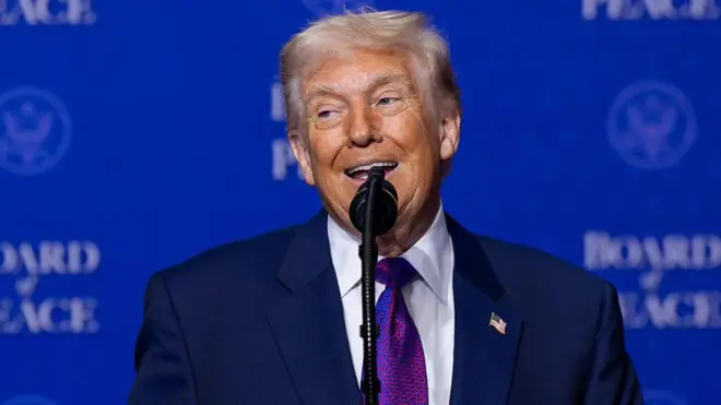 Trump hablando ante un micrófono, con un fondo azul donde se lee “Board of Peace”.