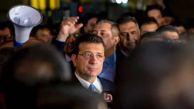 İmamoğlu uzakta bir noktaya bakıyor. Çevresinde kalabalık var. 