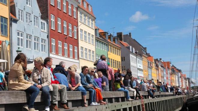 Pessoas sentadas na beira de um rio na Dinamarca