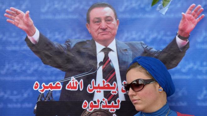 إحدى مؤيدات الرئيس المصري أمام ملصق تأييد له في عيد ميلاده خارج المستشفى حيث كان يعالج