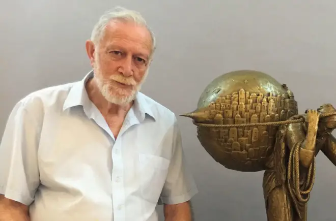 الفنان الفلسطيني سليمان منصور إلى جانب مجسم للوحته "جمل المحامل"