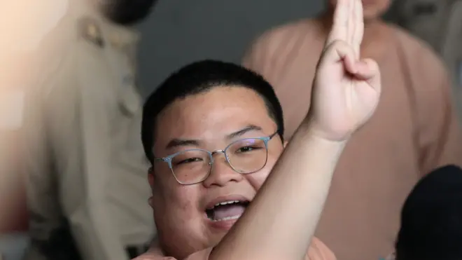 พริษฐ์ ชิวารักษ์ หรือ "เพนกวิน" 1 ใน 22 จำเลยคดีชุมนุม "19 กันยาทวงอำนาจคืนราษฎร" ชูสามนิ้วขณะที่เดินทางจากเรือนจำพิเศษกรุงเทพฯ มาถึงศาลอาญาวันนี้ (15 มี.ค.)