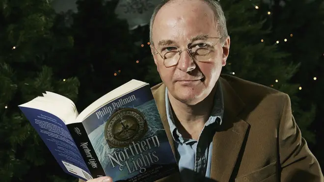 Philip Pullman sosteniendo su libro "Luces del norte"