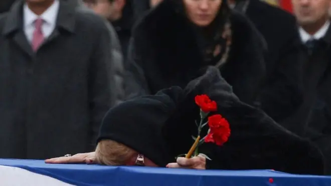 卡尔洛夫的遗孀趴在他的遗棺上哭泣。