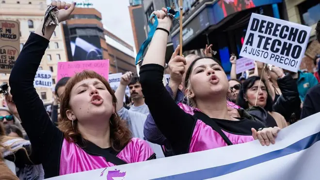 Dos jóvenes gritan con la mano alzada en una manifestación por el derecho a la vivienda en Madrid.