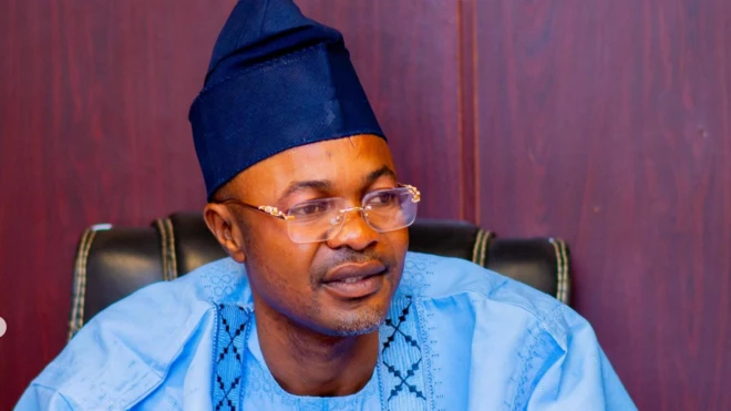 Adeniyi Adeyemi wọ asọ agbada toke tilẹ alawọ buluu ati fila rẹ, o jokoo sori aga