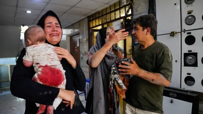 Una madre llora mientras sostiene a su bebé herido, tras un ataque israelí contra Teherán