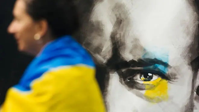 德國杜塞爾多夫一位身披烏克蘭國旗的女示威者站在Anna Movenko油畫作品前(29/10/2022)