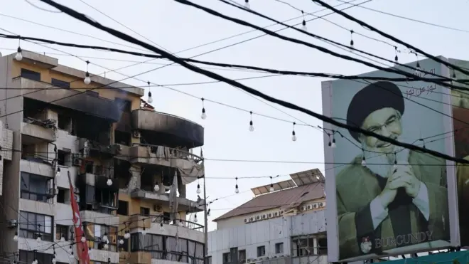 Поврежденное здание в Бейруте и портрет бывшего лидера "Хезболлы" Хасана Насраллы, который был убит в результате израильского авиаудара в 2024 году