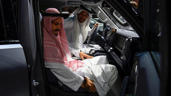 رجلان يرتديان زياً خليجياً يجلسان في مقصورة سيارة صينية الصُنع وأحدهما على كرسي القيادة