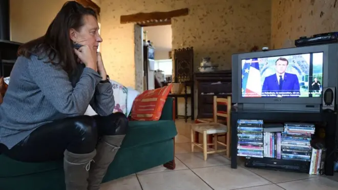 Bir hemşire Fransa Cumhurbaşkanı Macron'un açıklamalarını dinliyor