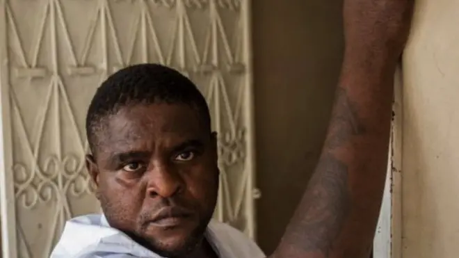 Jimmy Chérizier in a doorway, clutching a wall