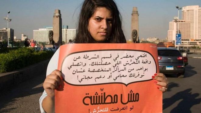فتاة تحمل لافتة تطالب الضحايا بعدم الخوف