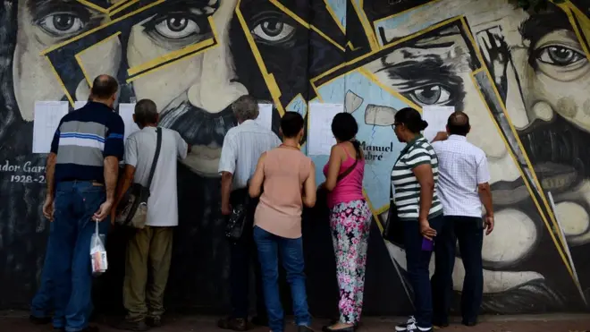 People look for their names on electoral rolls before voting in the municipal elections in Caracas on December 10, 2017.