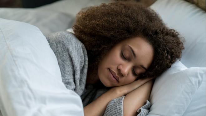 Imagem mostra mulher jovem dormindo numa cama
