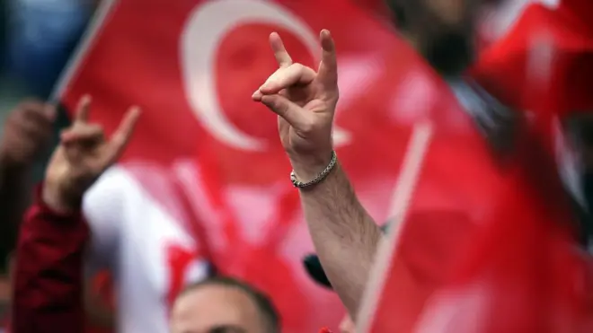 Close up of hands making wolf salute gesture