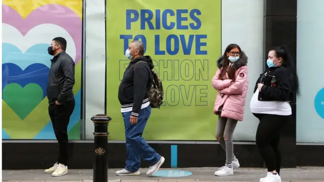 Shoppers queuing outside a shop in Manchester on 12 April