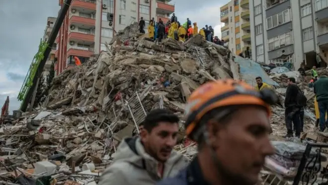 Des sauveteurs à pied d'oeuvre autour des décombres.