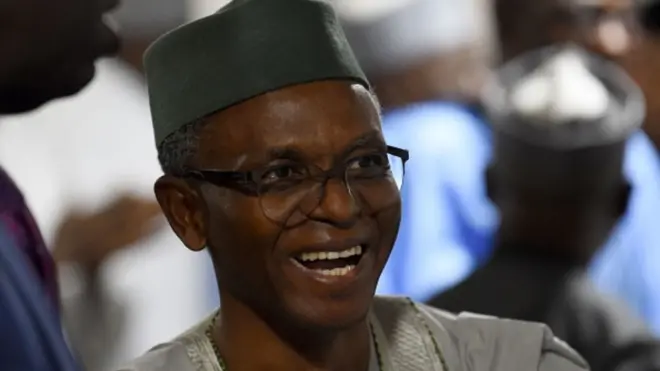 Embattled former Kaduna govnor Nasir El'Rufai dey laugh. E wear green traditional cap and agbada.