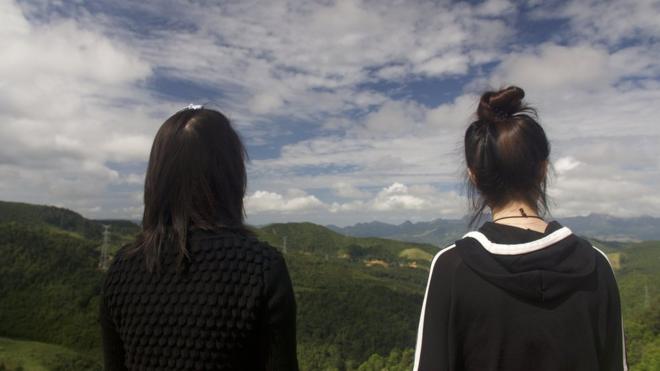 Now safely over the border Mira (L) and Jiyun (R) look out over a mountain range back towards China