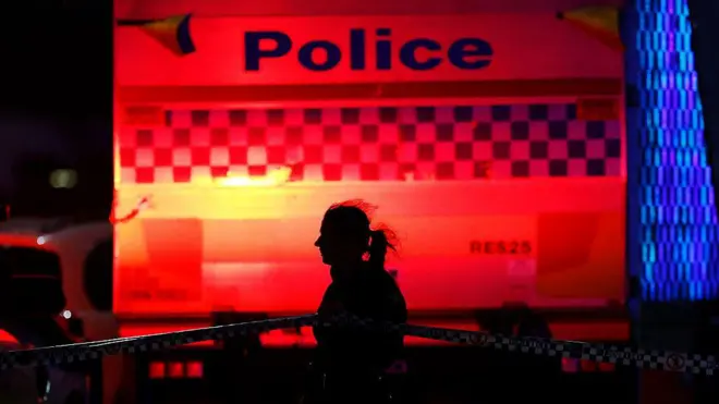 Полицейский идет вдоль ограждающей ленты на месте массовой стрельбы на Бонди-бич 14 декабря 2025 года.