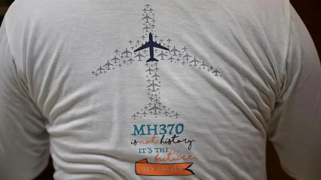 На этой фотографии, сделанной 10 декабря 2025 года, Цзян Хуэй, чья мать находилась на борту пропавшего рейса MH370 авиакомпании Malaysia Airlines, запечатлен в своей квартире в Пекине в футболке, посвященной этой катастрофе.