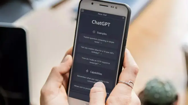 يد تمسك هاتفًا يظهر فيه تطبيق "تشات جي بي تي" أثناء محادثة.