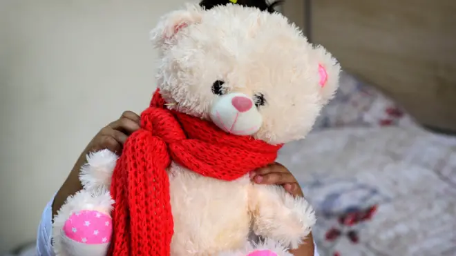 አሻንጉሊት የያዘች ህፃን