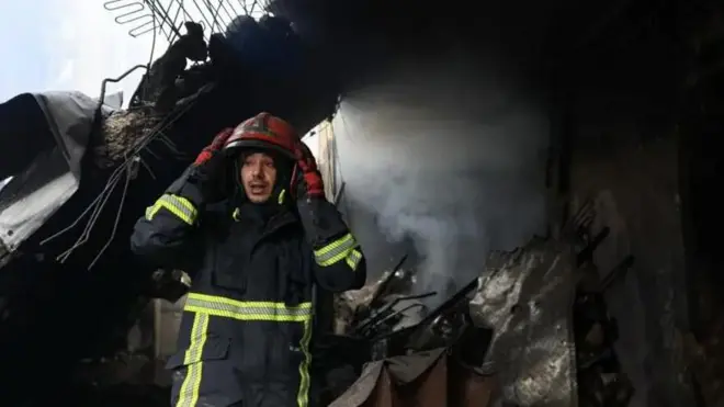 Пожарный на фоне почерневших развалин